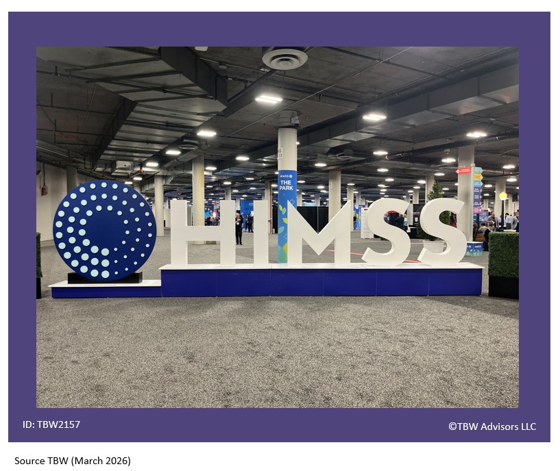 BIg blue round circle with three inner circle of dots. to the left of HUGE H I M S S letters - life size letters. An obvious place people take pictures for social media. Exhibits and attendees seen in the distant background.
